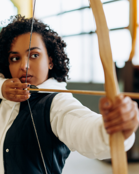 Person holding a drawn bow ready to fire an arrow